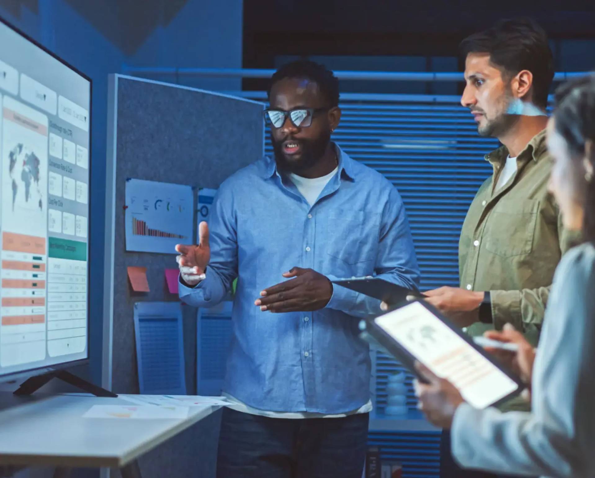 Team members collaborating on a tech project with a touchscreen interface.
